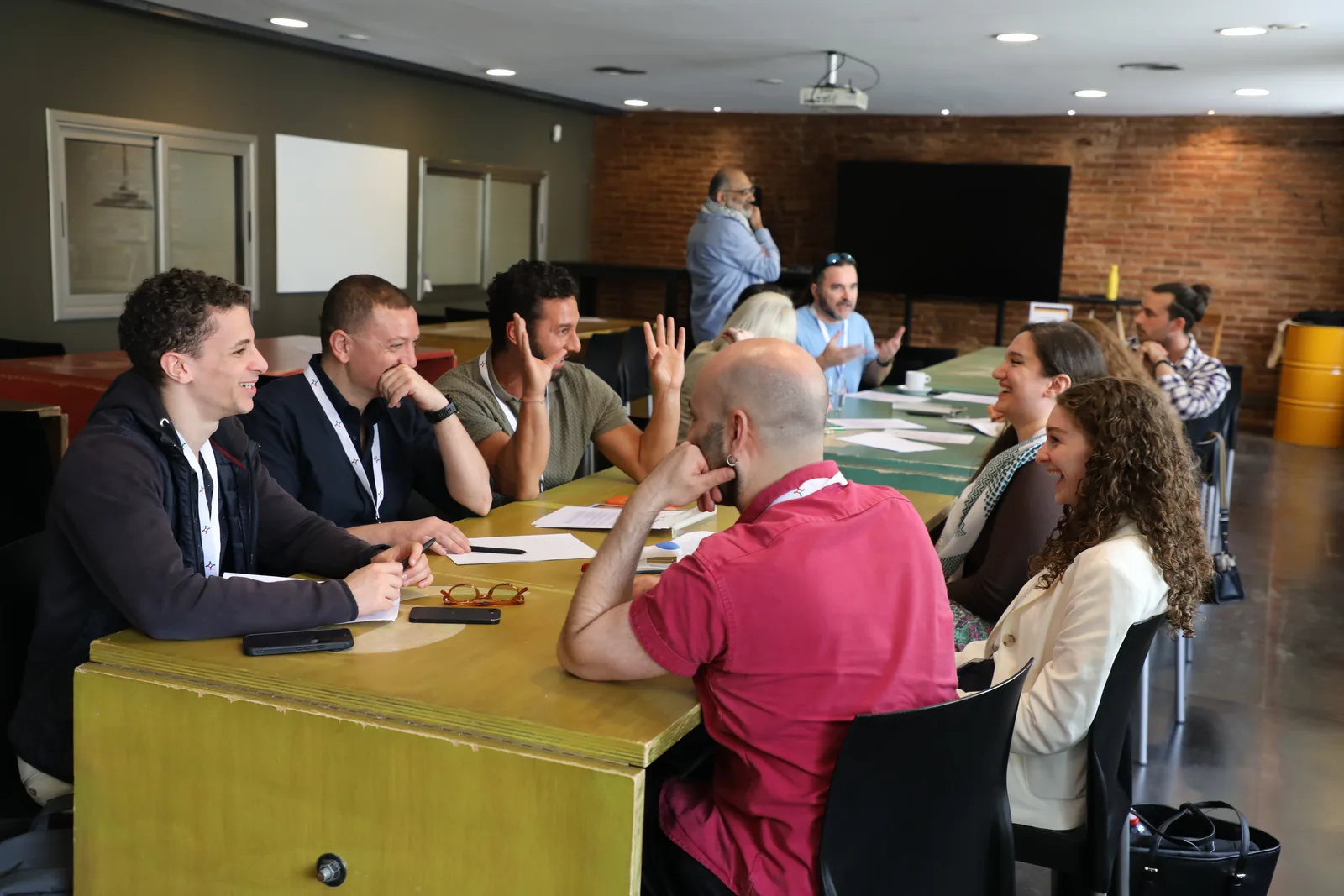 Hackathon participants laughing and debating ideas around a long workshop table